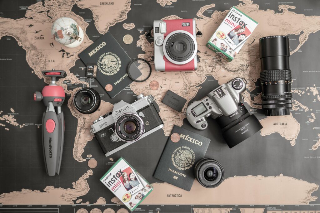 Flat lay of vintage cameras, passports, and travel essentials on a world map.